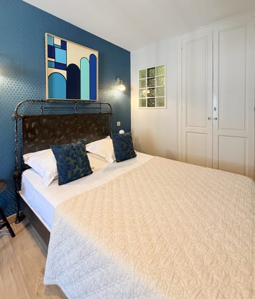 Habitación moderna en el Hôtel La Suite de Villeneuve-lès-Avignon con pared azul, cama metálica y vistas a la ciudad