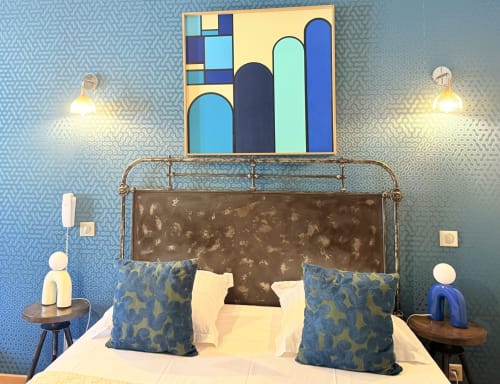 Dormitorio moderno en el Hôtel La Suite de Villeneuve-lès-Avignon con almohadas azules estampadas, arte geométrico sobre cama de hierro forjado