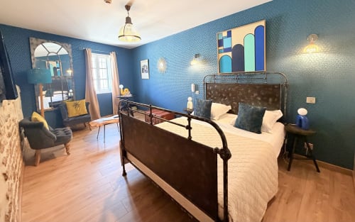 Habitación moderna azul en el Hôtel La Suite con cama de hierro forjado, suelos de madera y vistas a la ciudad en Villeneuve-lès-Avignon