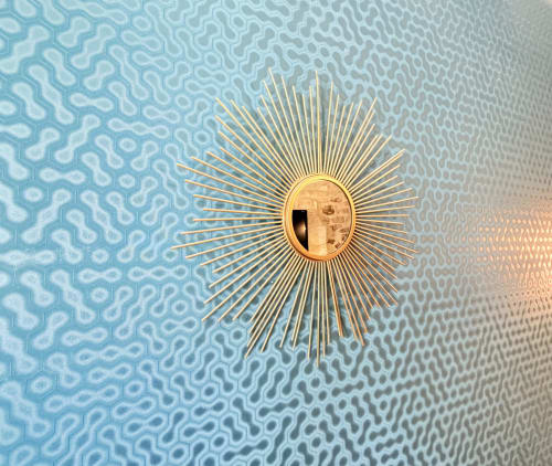 Espejo de rayos dorados sobre pared azul con patrón en una habitación del Hôtel La Suite, Villeneuve-lès-Avignon