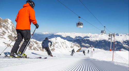 Skieurs sur les pistes enneigées de Courchevel avec remontées mécaniques et pics alpins sous un ciel bleu dégagé