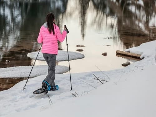 Femme en raquettes le long d'une rivière hivernale près de Zoppas Courchevel, Alpes