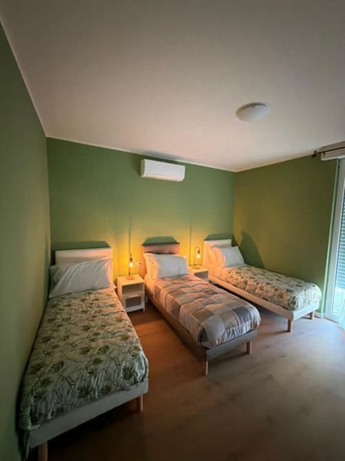 Camera tripla presso 88 Destination BnB a Treviglio con tre letti singoli, pareti verdi e illuminazione calda