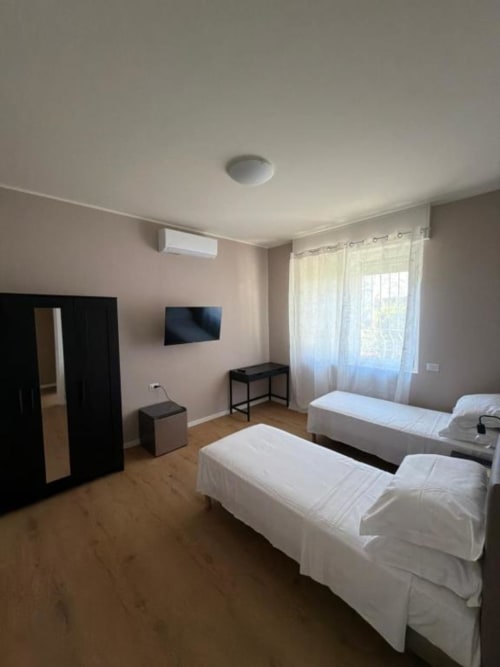 Camera matrimoniale deluxe presso 88 Destination a Treviglio con due letti, TV, armadio e vista sulla città dalle ampie finestre