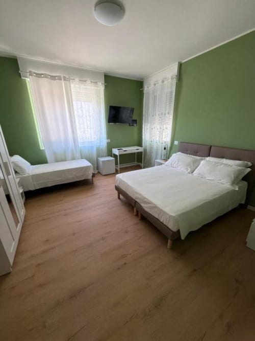Camera tripla presso 88 Destination B&B a Treviglio con letto matrimoniale, letto singolo, TV, pareti verdi e pavimento in legno