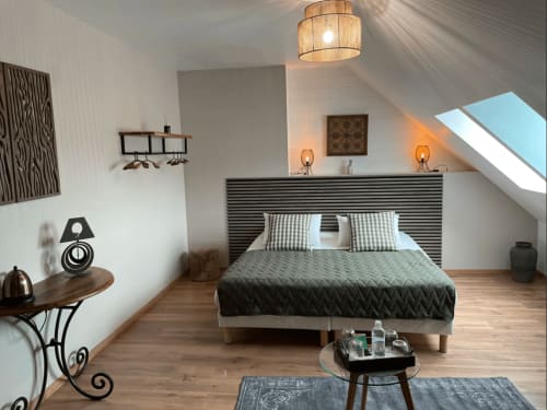 Chambre mansardée moderne au Clos De La Gourmandiere avec poutres apparentes, velux, tête de lit rayée et mobilier élégant