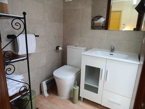 Baño moderno en la villa Alojamientos Las Mellis en Antequera con lavamanos blanco, inodoro y toallero decorativo