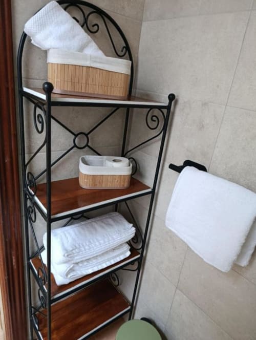 Estantería de baño con toallas blancas dobladas y cestas de almacenamiento en la villa Las Mellis, Antequera, España