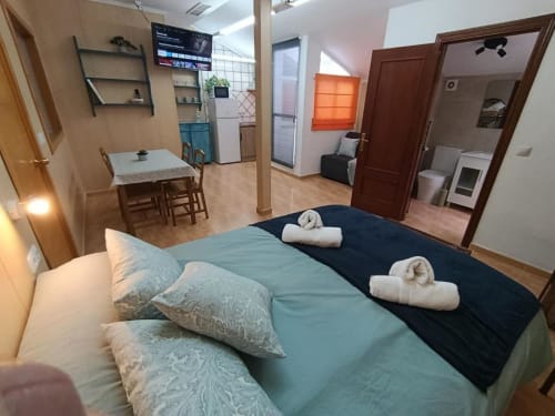 Amplio dormitorio en Villa Sol, Antequera, con cama matrimonial, toallas blancas, comedor, cocina y acceso al baño