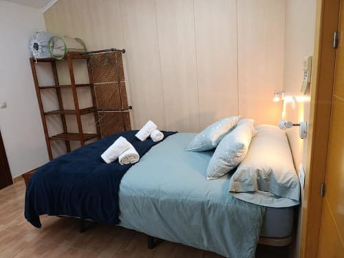 Dormitorio en villa Alojamientos Las Mellis en Antequera con cama doble, ropa de cama azul, almohadas, toallas enrolladas y detalles de madera