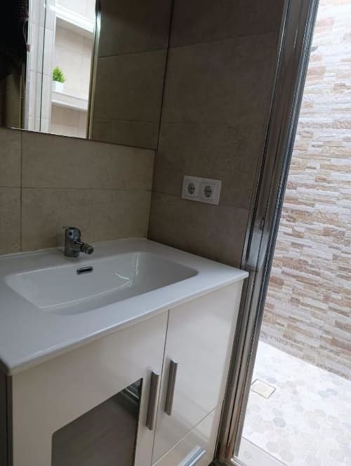 Baño moderno en villa Las Mellis con tocador blanco, paredes de azulejos marrones y espejo en Antequera