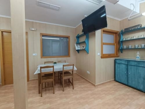 Comedor de la villa Sol en Alojamientos Las Mellis, Antequera, con mesa de madera, sillas, televisor y estanterías azules