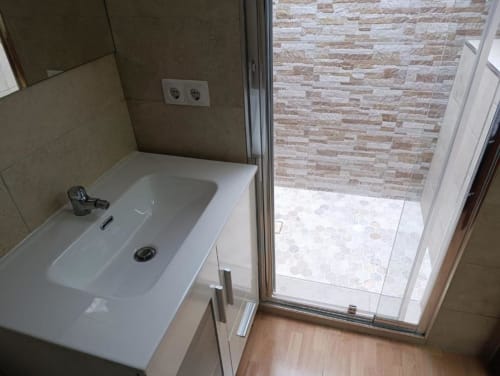 Baño moderno con lavabo blanco, paredes alicatadas y ducha tipo walk-in en villa Las Mellis, Antequera