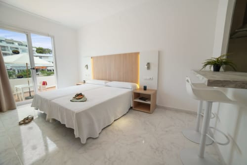 Apartamento luminoso en Apartamentos Playa Sol, Es Canar, con cama moderna, cabecero de madera y vistas al balcón