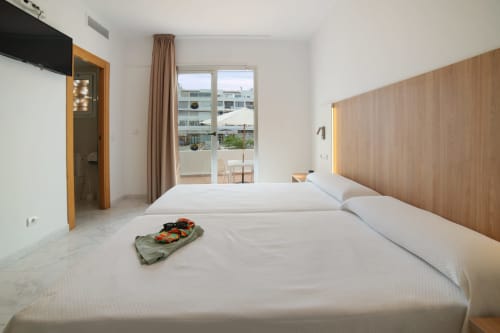 Luminoso estudio en Playa Sol con camas gemelas, cabecero de madera, balcón con vistas a la montaña y comodidades modernas
