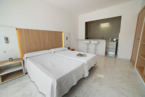Dormitorio de estudio en Apartamentos Playa Sol en Es Canar con camas individuales, cocina y comodidades modernas