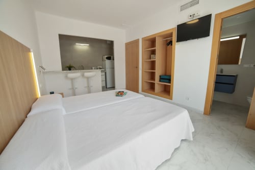Dormitorio moderno en estudio de Apartamentos Playa Sol en Es Canar con camas gemelas, cocina americana, baño y detalles en madera
