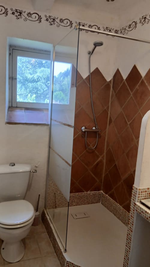Salle de bain moderne avec douche carrelée en losanges bruns, paroi vitrée et vue sur les montagnes à La Ribeyrette B&B à Chamborigaud
