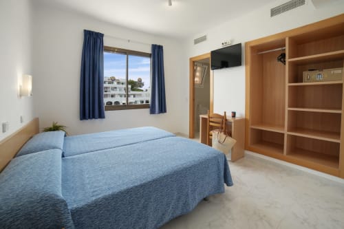 Luminoso apartamento estándar en Apartamentos Playa Sol, Es Canar con camas individuales, muebles de madera y balcón con vista a la montaña
