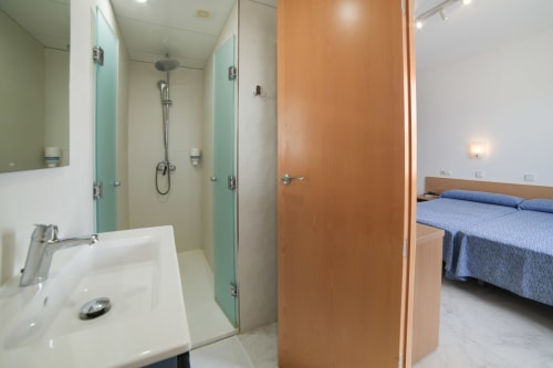 Baño moderno con ducha de vidrio y vista al dormitorio, Apartamentos Playa Sol