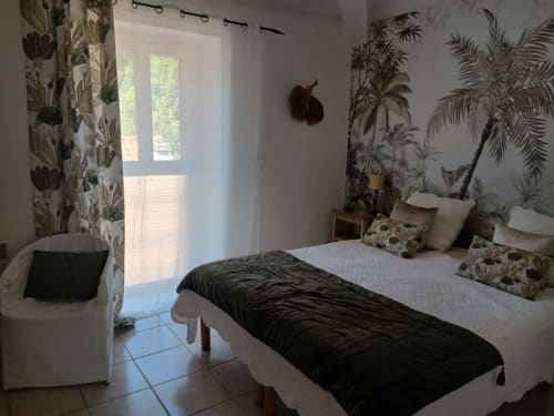 Chambre tropicale du gîte La Ribeyrette à Chamborigaud, décorée de papier peint botanique et de plantes palmiers
