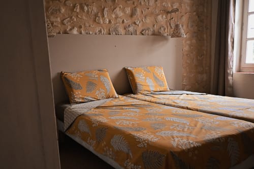 Chambre twin douillette au gîte Mas De La Digue à Châteaurenard, avec parure orange et murs en briques rustiques