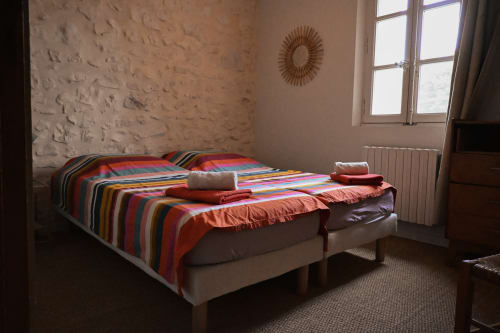 Lits jumeaux avec parure de lit rayée colorée dans une chambre aux murs en pierre du Mas De La Digue à Châteaurenard
