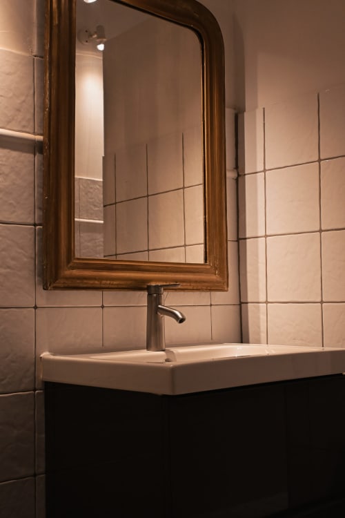 Lavabo de salle de bain avec miroir en bronze et murs carrelés à la Mas De La Digue, Châteaurenard