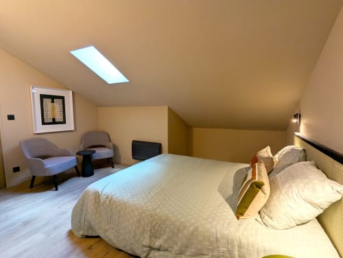Chambre mansardée moderne au gîte Domaine Alga avec lit queen-size, puits de lumière, coin salon et parquet