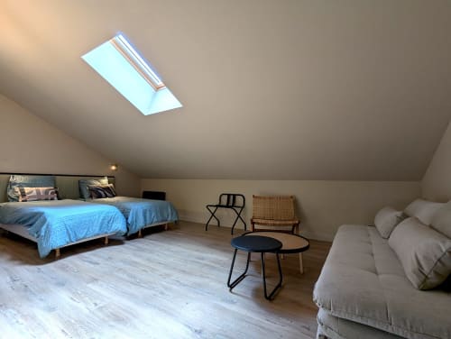 Spacieuse chambre mansardée au gîte Domaine Alga à Bourg-Charente avec claustras, lit, canapé et mobilier moderne