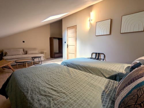 Chambre spacieuse au Domaine Alga à Bourg-Charente avec deux lits, coin salon, puits de lumière et décoration moderne