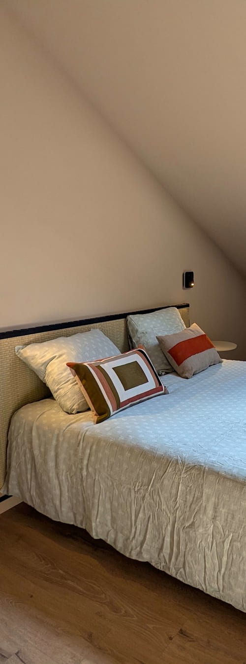 Chambre douillette du gîte Domaine Alga à Bourg-Charente avec literie crème, coussins décoratifs et tête de lit beige