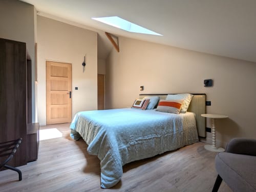 Chambre moderne du gîte Domaine Alga à Bourg-Charente avec puits de lumière, literie bleue et mobilier contemporain