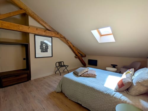 Chambre mansardée du Domaine Alga avec poutres apparentes, vélux, lit et équipements modernes à Bourg-Charente