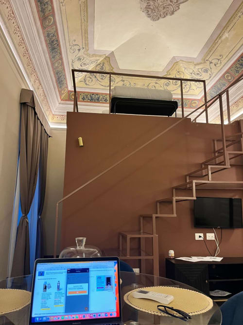 Elegant frescoed loft at Palazzo sul Corso Brindisi with ornate ceiling, modern workspace, and staircase