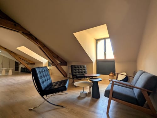Salon mansardé moderne au Gîte du Domaine Alga avec verrières, fauteuils en cuir noir et charpente apparente