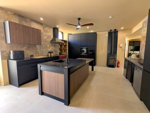 Cuisine moderne du gîte Domaine Alga à Bourg-Charente avec meubles noirs, îlot central et électroménagers inox