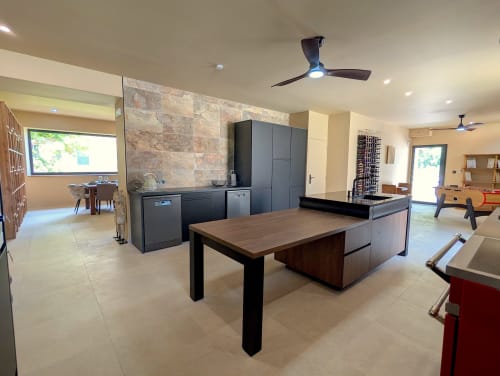Cuisine et salon de cottage moderne au Domaine Alga avec mobilier sombre, table à manger en bois et mur en pierre