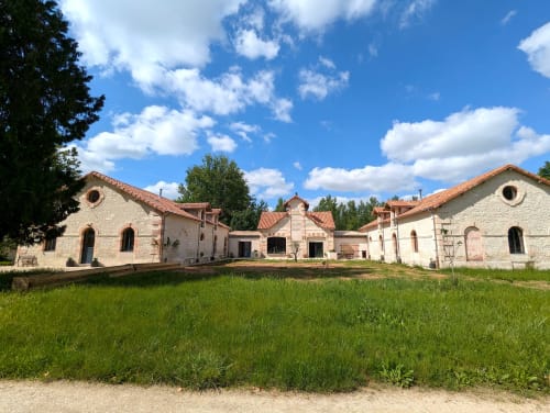 Cottage du Domaine Alga à Bourg-Charente avec bâtisses en pierre blanche et jardins verdoyants sous ciel bleu