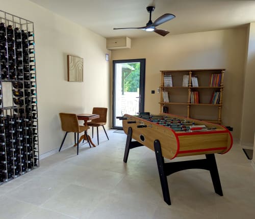 Salle de loisirs du gîte Domaine Alga avec baby-foot, bibliothèque, coin détente et cave à vin
