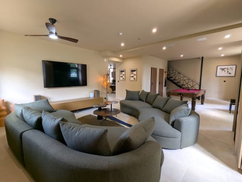 Spacieux salon du gîte Domaine Alga avec canapé gris courbe, télévision, ventilateur de plafond, billard et éclairage moderne