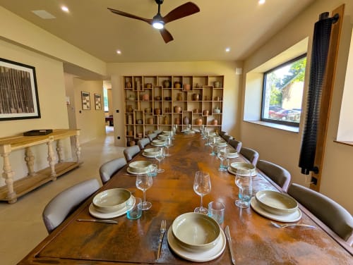 Élégante salle à manger du gîte Domaine Alga avec table dressée, couverts, étagères en bois et ventilateur de plafond
