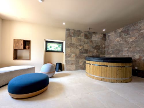 Spa moderne au gîte Domaine Alga avec bain chaud en bois, pouf bleu et murs en ardoise