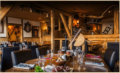 Salle à manger rustique à Zoppas Courchevel avec poutres en bois, couverts élégants, verres à vin et ambiance de lodge montagnard