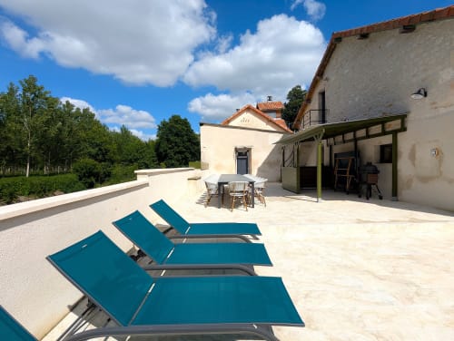 Terrasse du Domaine Alga avec chaises longues bleues, coin repas et vue sur la campagne de Bourg-Charente