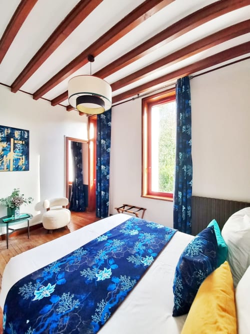 Chambre deluxe à la Villa Eliane avec parure de lit bleue à motifs, poutres en bois et vue sur le jardin à Étretat