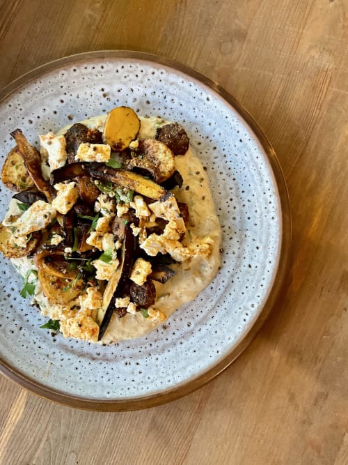 Gourmet plated dish at Domaine Alga with roasted vegetables, protein, and creamy sauce on speckled plate