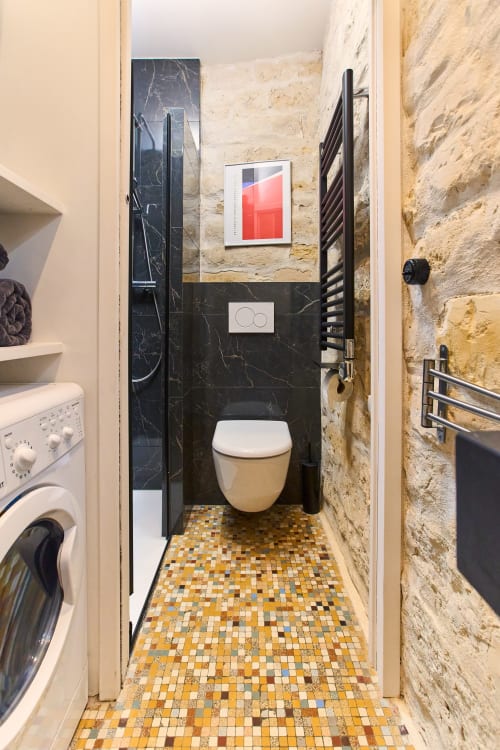 Salle de bain moderne au Loft Menilmontant de Boutik Boheme Paris avec toilettes murales, carrelage marbre noir et sol en mosaïque