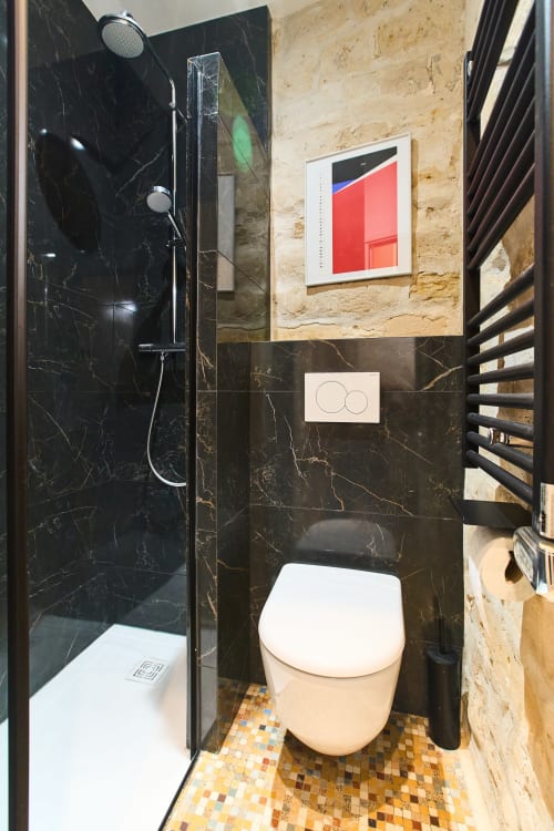 Salle de bain moderne au Loft Menilmontant chez Boutik Boheme Paris avec carrelage en marbre noir, toilettes blanches et douche