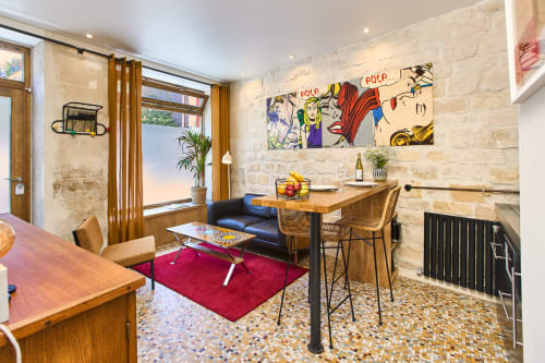 Modern loft apartment at Boutik Boheme Paris with pop art décor, wooden furniture, red rug, and stone walls